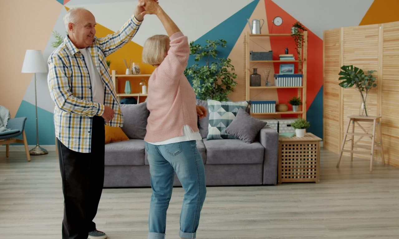 Un couple de personnes âgées danse dans son salon