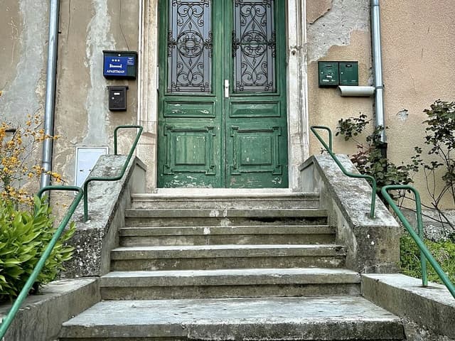 Un perron de pierre à quelques marches, devant une porte d’entrée