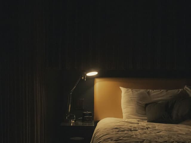 Une lampe de chevet allumée dans une chambre, la nuit