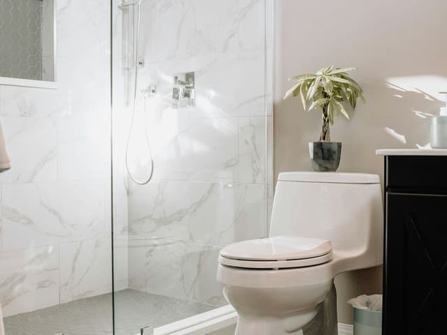 Une salle de bains avec une douche de plain-pied à porte vitrée